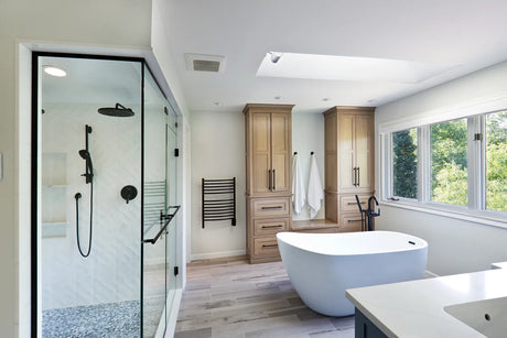 Filled freestanding bathtub resting on a wood floor in a bright modern bathroom