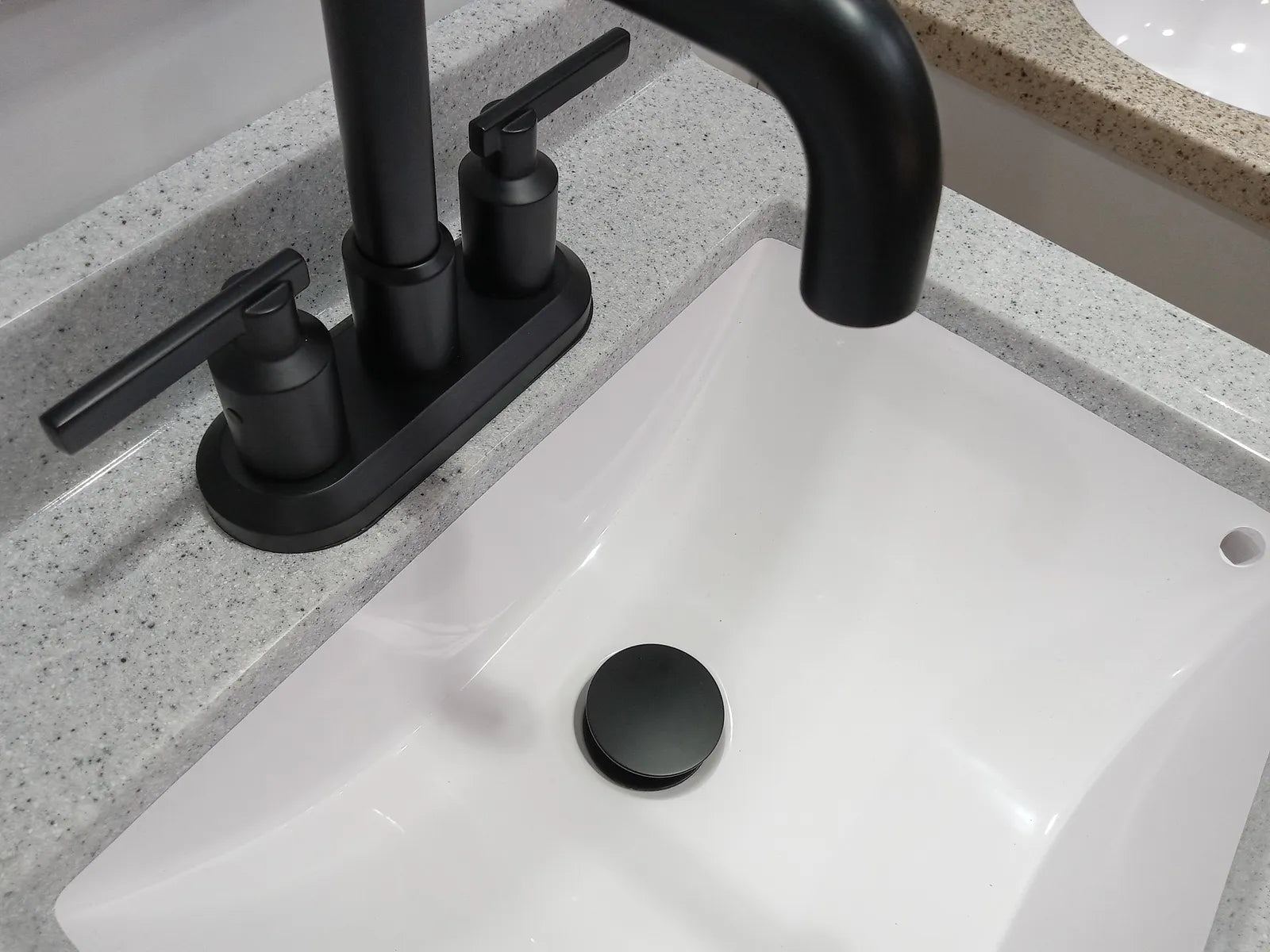 Matte black pop-up sink drain matching a matte black bathroom faucet on a white basin