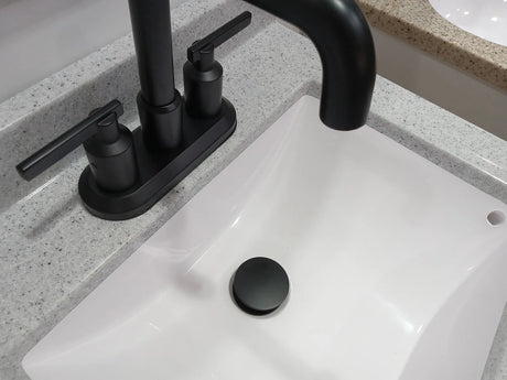 Matte black pop-up sink drain matching a matte black bathroom faucet on a white basin