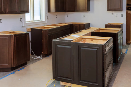 Stainless steel undermount kitchen sink being fitted into a base cabinet during a kitchen renovation
