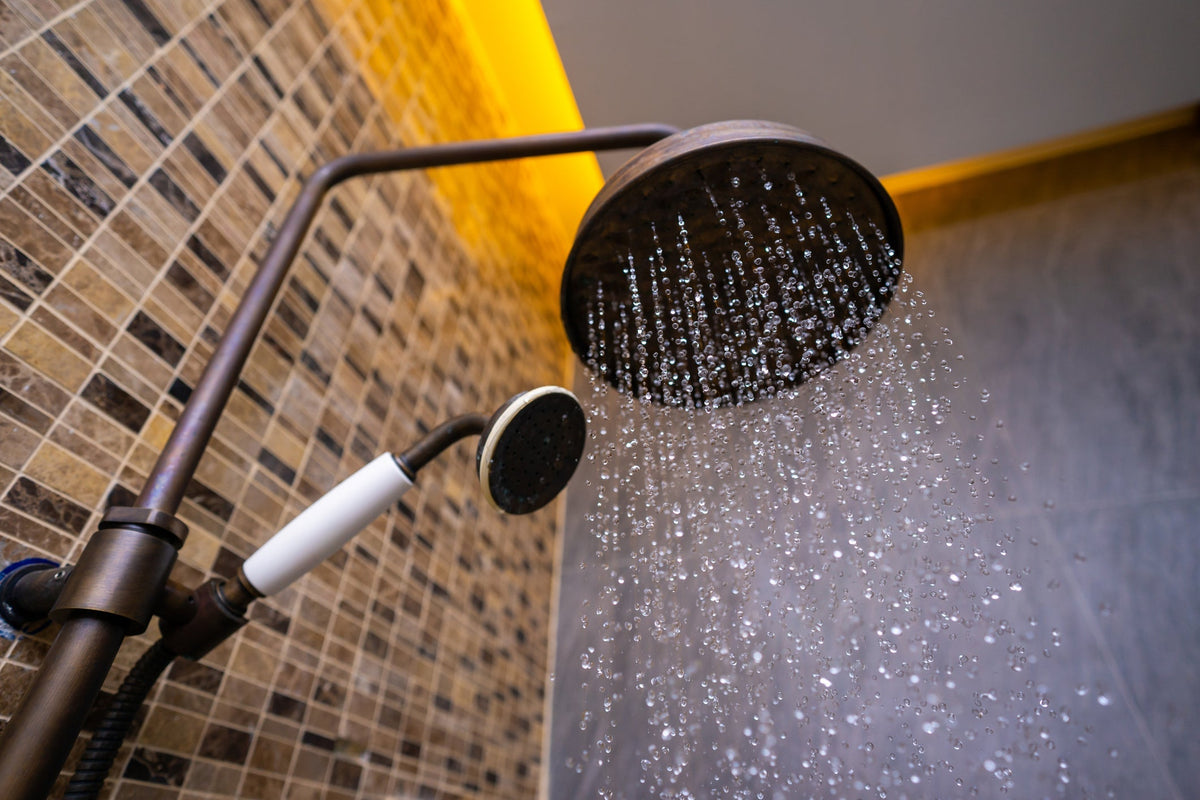 Slim modern rain shower head with hand shower in a warm-toned Canadian bathroom