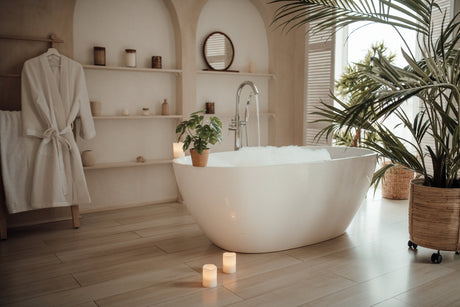 Freestanding bathtub with brushed brass tub filler in a warm neutral bathroom