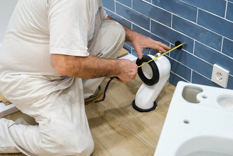 Plumber measuring and installing a toilet drain flange during installation