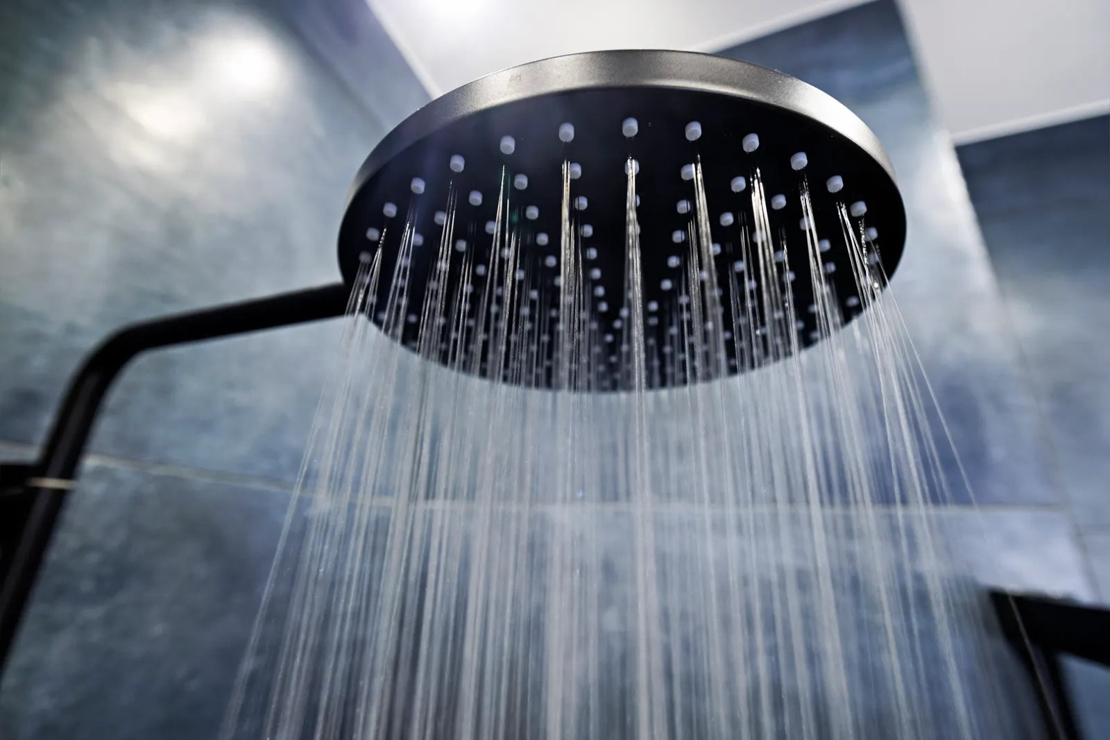 Rain shower head and hand shower running in a modern tiled walk-in shower