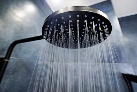Rain shower head and hand shower running in a modern tiled walk-in shower