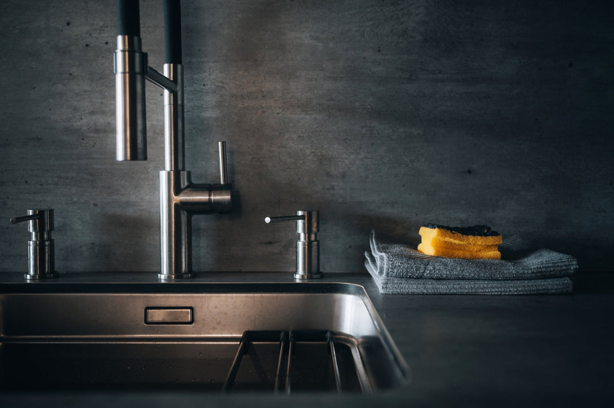 Built in soap dispenser mounted beside a stainless steel kitchen faucet on a quartz countertop