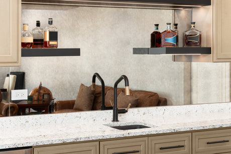 Compact stainless steel bar sink with a black faucet in a modern home wet bar