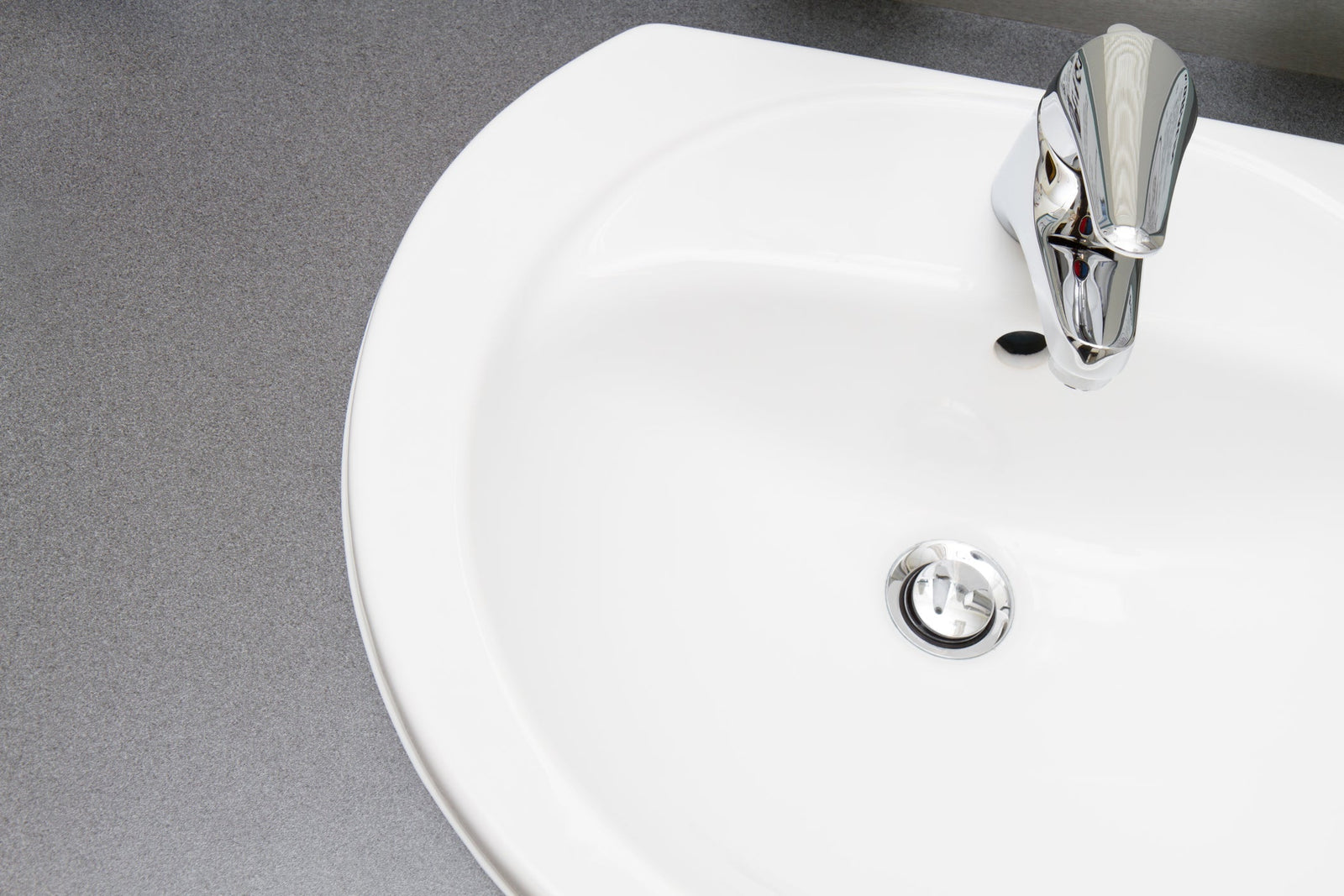 Polished chrome P-trap and drain assembly beneath a white wall-mounted bathroom sink