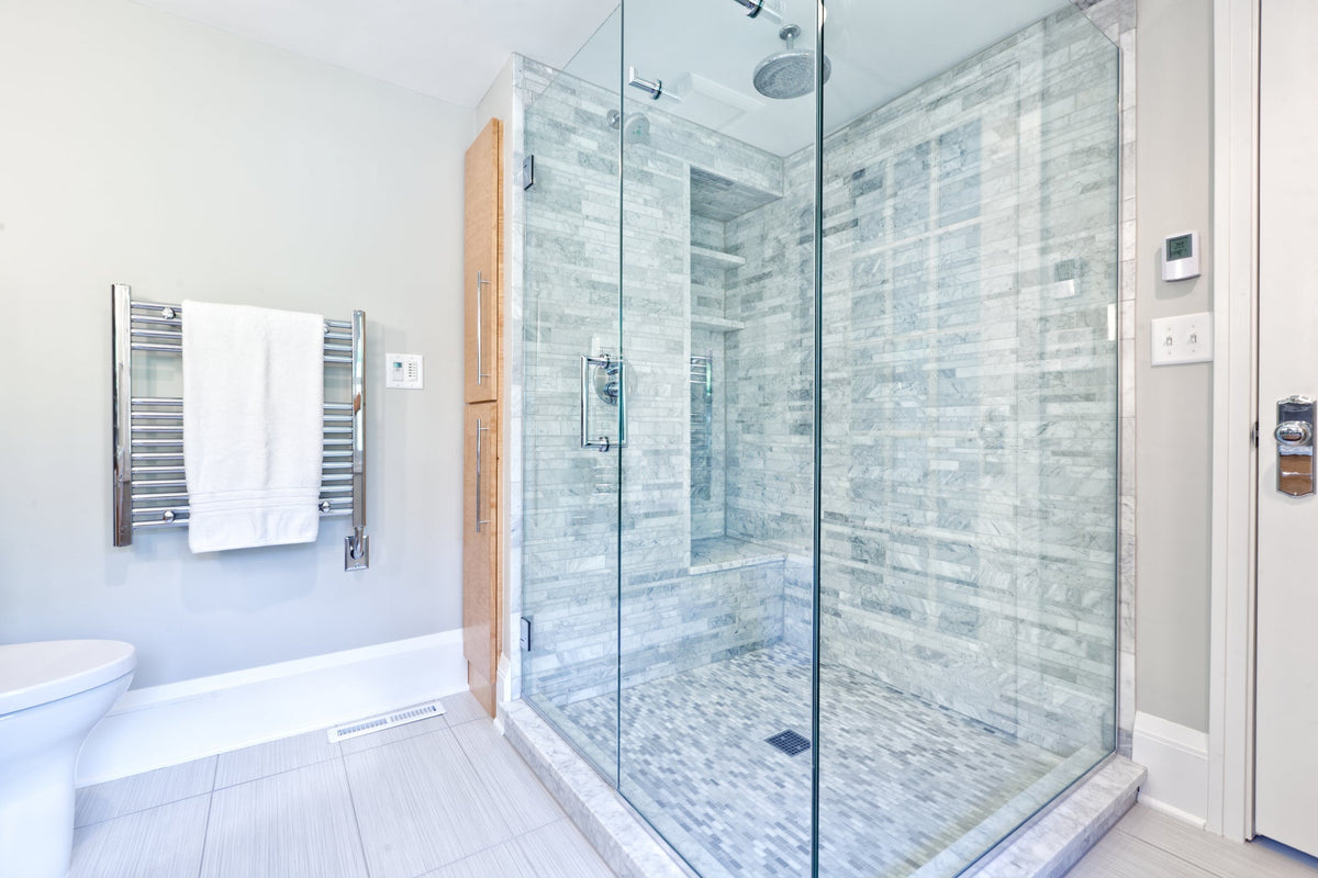 Semi-frameless sliding glass shower door installed in a bright modern bathroom alcove