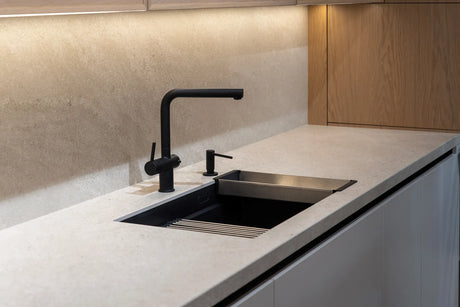 Close-up of a matte black kitchen faucet with water droplets on its finish