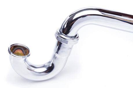 Polished chrome P-trap and drain assembly beneath a bathroom sink against a tiled wall