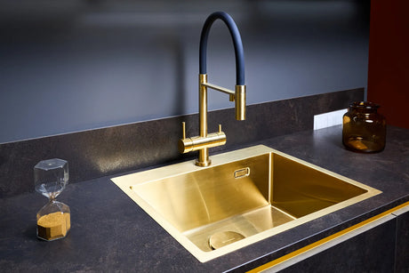 Close-up of a polished solid brass luxury kitchen faucet mounted on a marble countertop