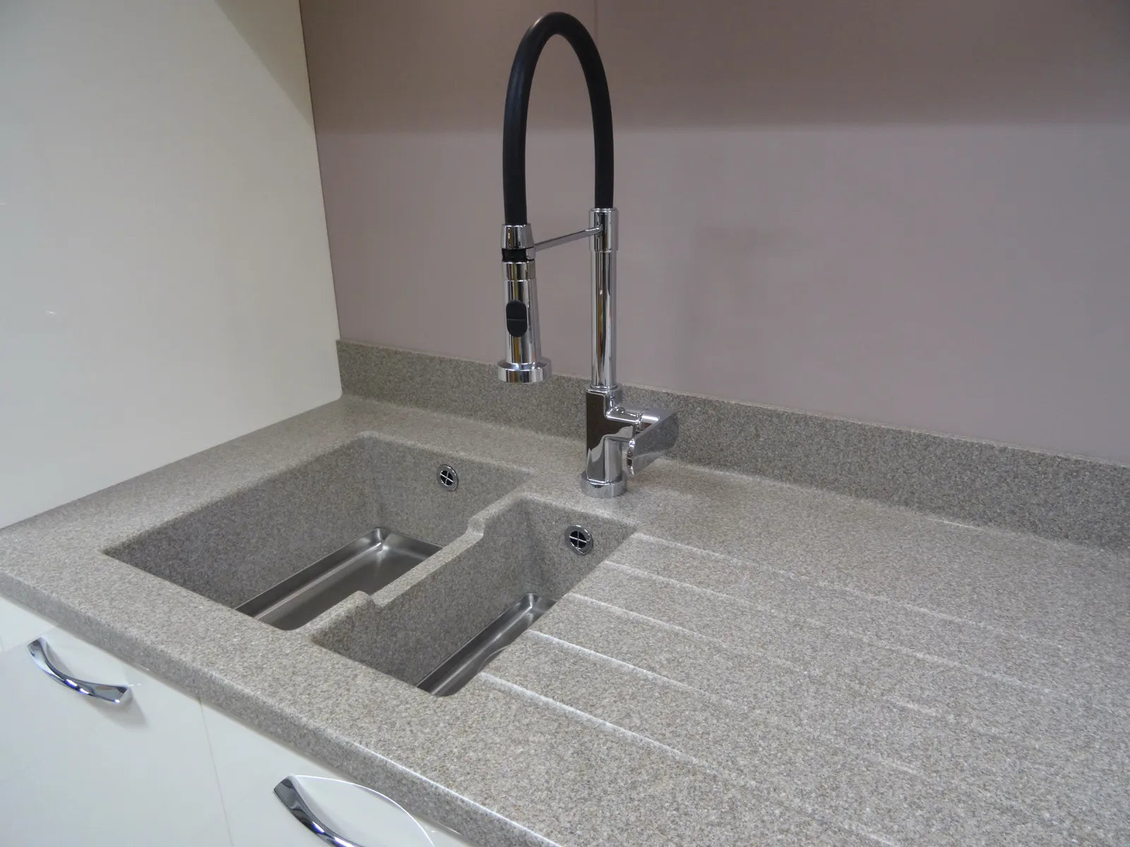 Dark granite composite kitchen sink with faucet set into a stone countertop in a modern kitchen
