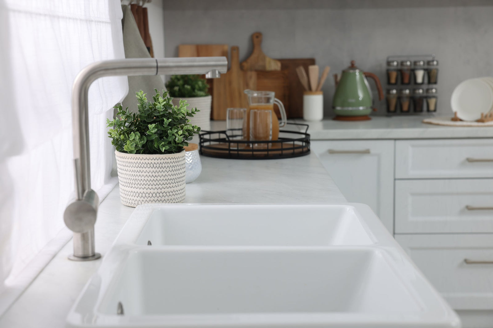 Undermount stainless steel kitchen sink with pull-down faucet in a bright modern kitchen