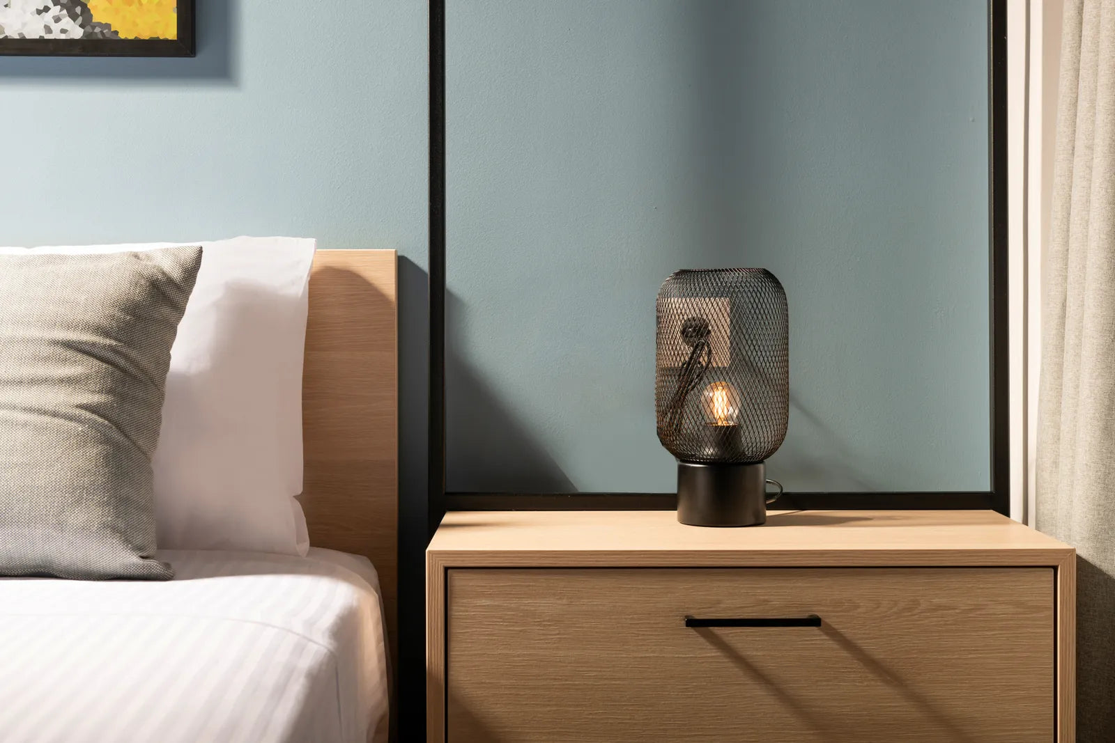 Modern bedroom with a slim wall sconce mounted beside the bed at reading height above the nightstand