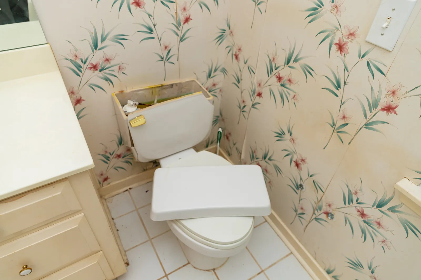 Homeowner lifting the lid off a white two-piece toilet tank to check the model number inside