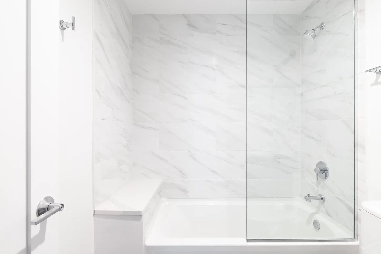 Bright bathroom with a white alcove bathtub, tiled surround and a glass shower door