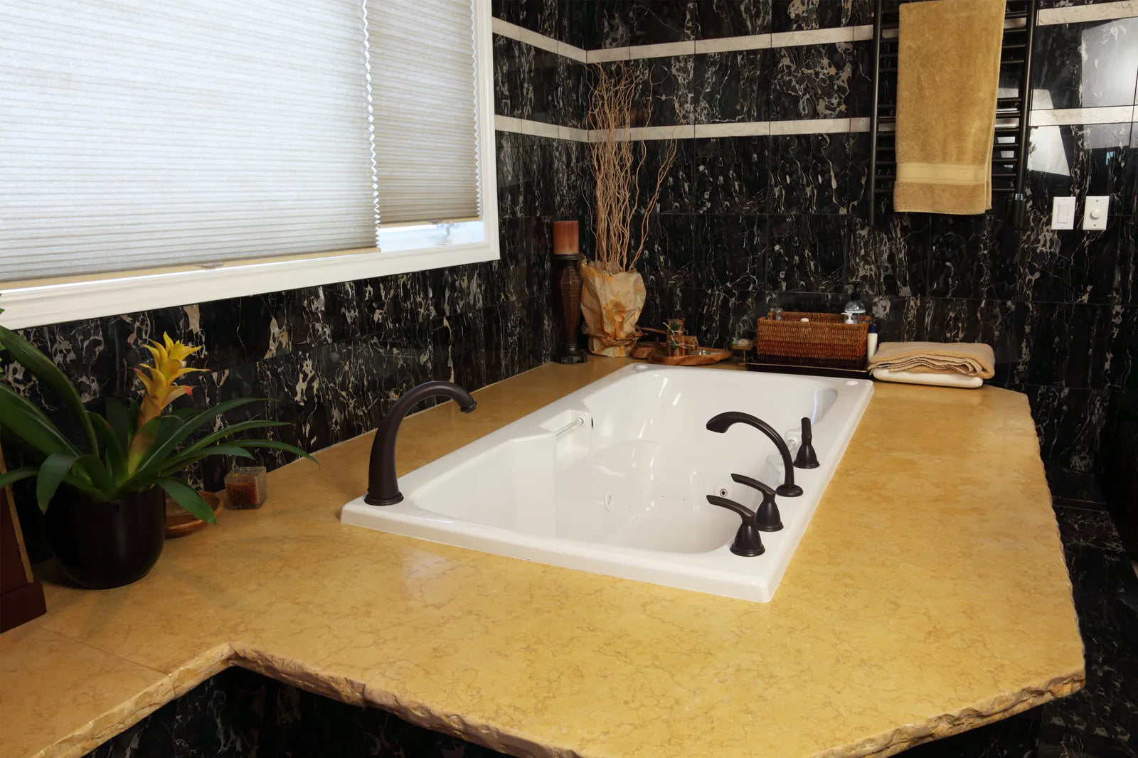 Undermount bathtub set into a polished stone tub deck in a modern bathroom