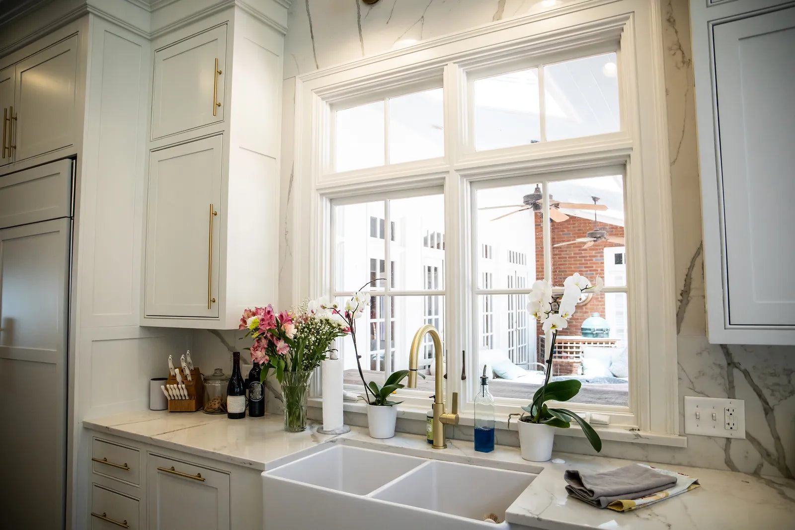 Traditional kitchen with a white fireclay apron-front sink and a polished bridge faucet above it