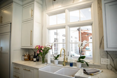 Traditional kitchen with a white fireclay apron-front sink and a polished bridge faucet above it