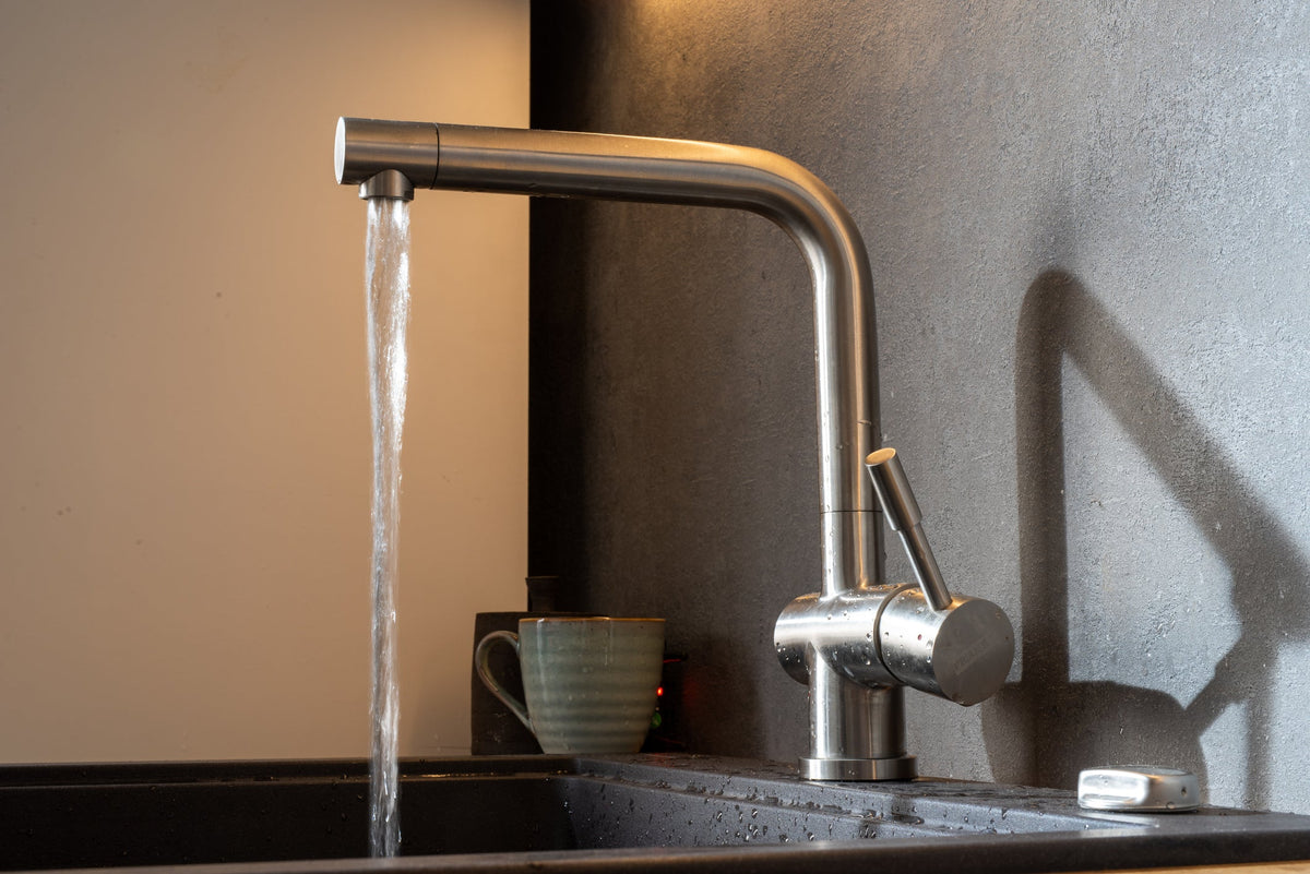 Pull-down kitchen faucet in a brushed finish arched over a stainless steel kitchen sink